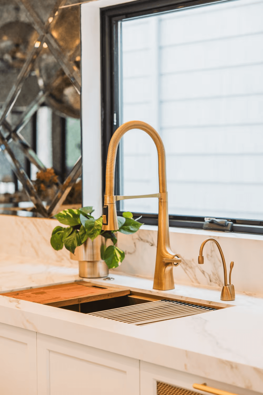Awning window above a marble kitchen counter with brass faucet